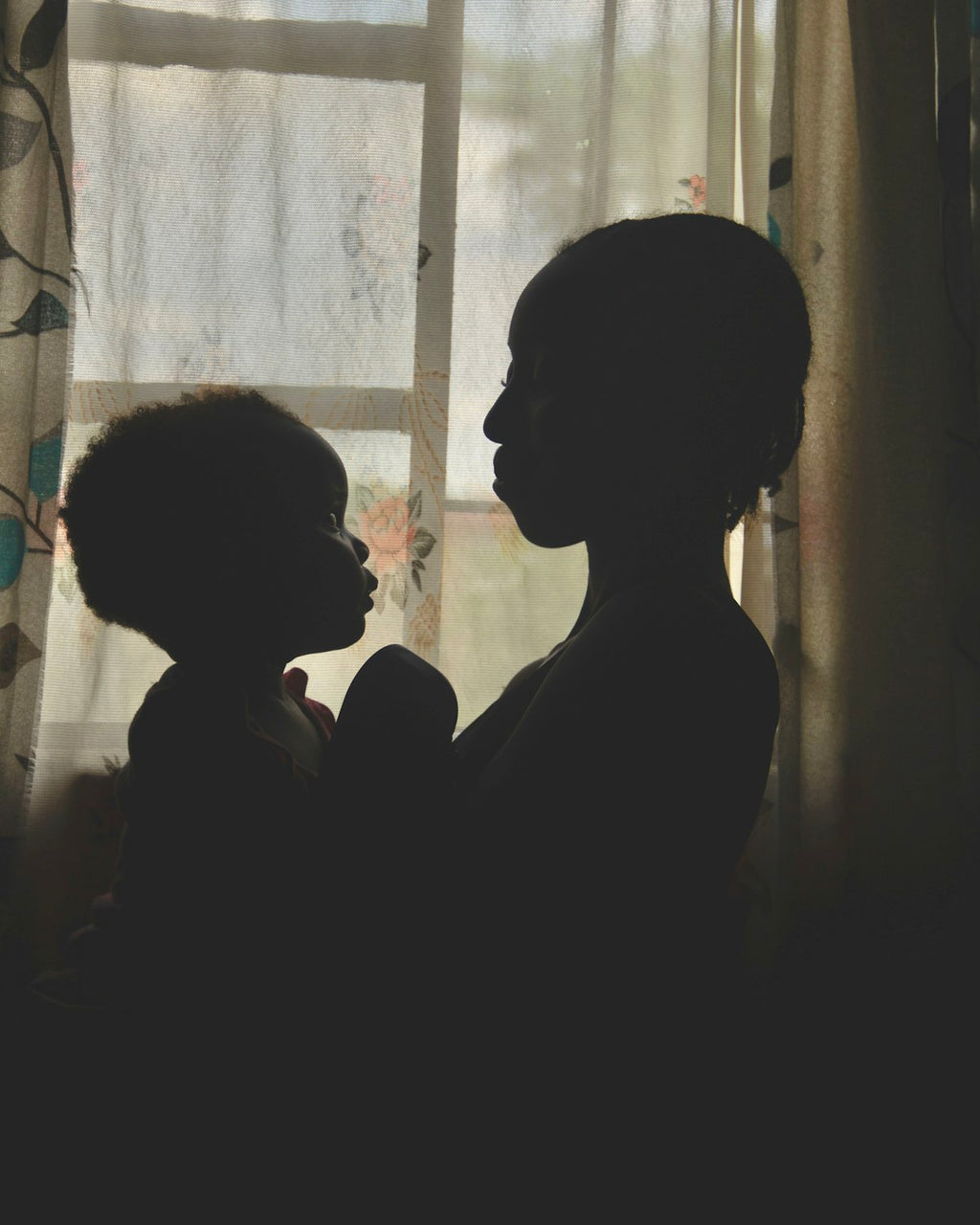 Mother holding her child in backlight by a window