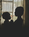 Mother holding her child in backlight by a window